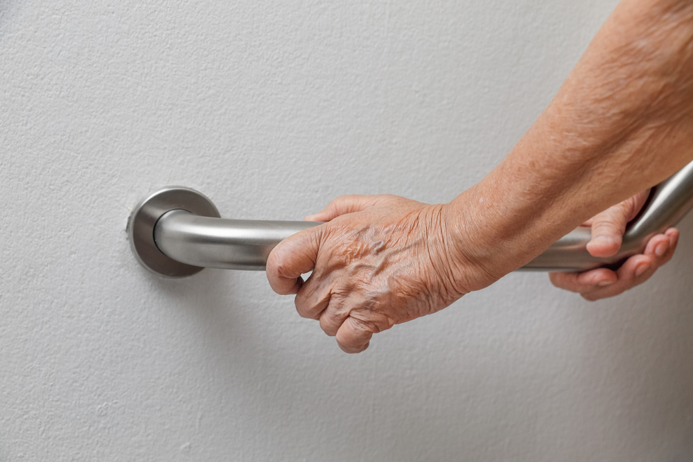 Elderly,woman,holding,on,handrail,for,safety,walk,steps